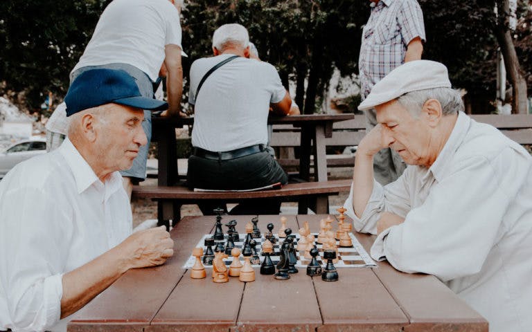 Two older men play chess.